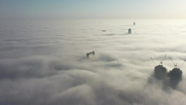 Aerial view of Dubai frame and other skyscrapers covered in fog