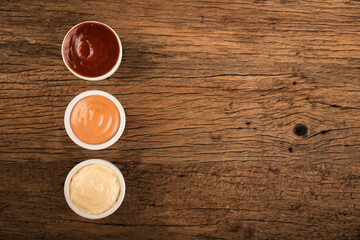 Ketchup, mayonnaise and rose sauce on rustic wooden background