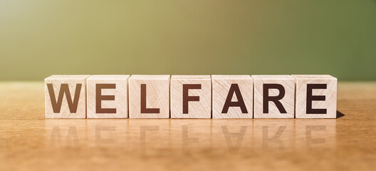 WELFARE word written on wooden blocks on wooden table. Concept for your design.