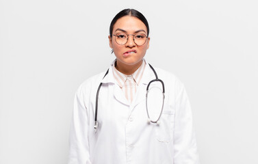 hispanic woman looking puzzled and confused, biting lip with a nervous gesture, not knowing the...