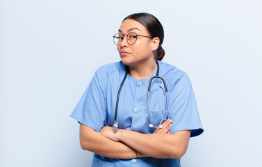 hispanic woman shrugging, feeling confused and uncertain, doubting with arms crossed and puzzled...