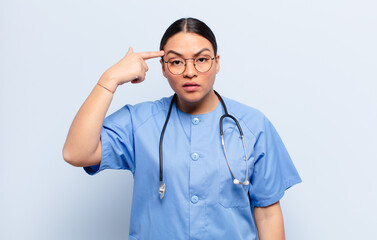 hispanic woman feeling confused and puzzled, showing you are insane, crazy or out of your mind