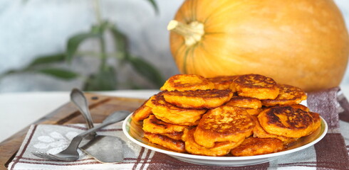 Diet healthy food idea.Fried pumpkin pancakes in a plate on the background of a large orange pumpkin.