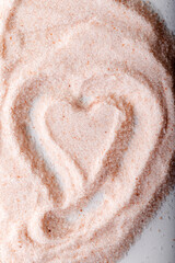Pink Himalayan salt powder with a heart-shaped mark on it. Food background.