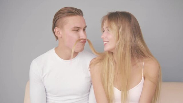 Guy makes a mustache from a strand of girl's hair