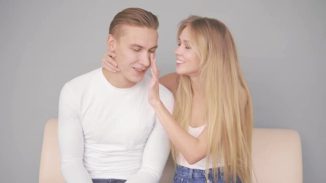 A young woman gently strokes her boyfriend's face