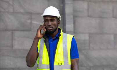 Portrait of African american Technician Electrical Engineer talki on mobile phone at modern building. Clean and green alternative energy concept.