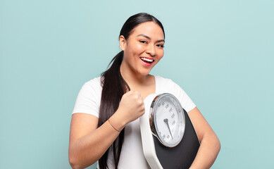 hispanic woman feeling happy, positive and successful, motivated when facing a challenge or celebrating good results