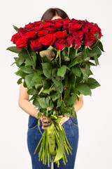 The girl with big bouquet of red roses in front of her