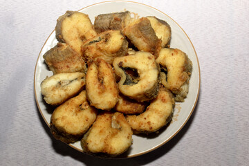Fresh fried fish in pieces laid out on a plate top view