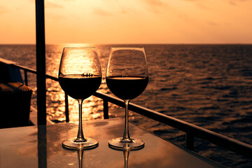 Glasses, red wine and tropical sunset with sea background, nobody.