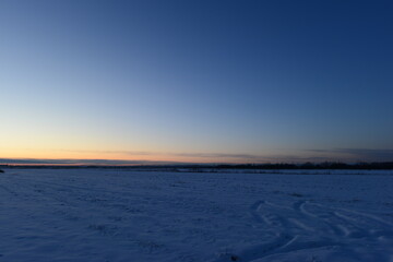 Fototapeta na wymiar Winter dusky blue sky in a rural area over snowy fields