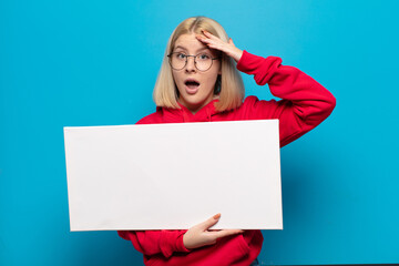 blonde woman looking happy, astonished and surprised, smiling and realizing amazing and incredible...