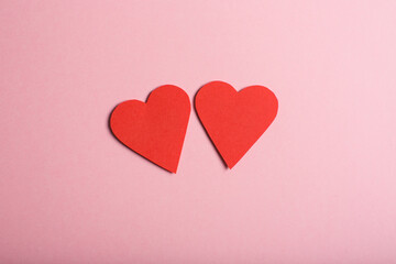 Two paper hearts on pink background.