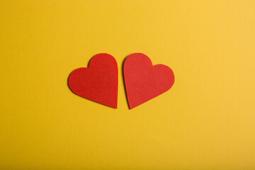 Two paper hearts on yellow background