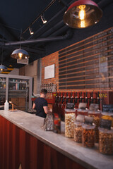 Vertical shot of beer pub with snacks on the counter and bartender pouring beer on background