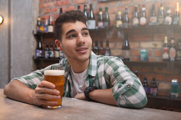 Happy handsome young man enjoying beer at the pub, copy space