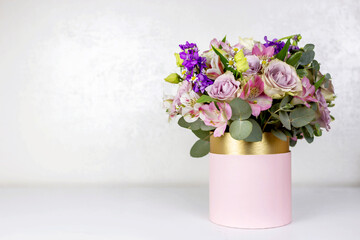 Beautiful bouquet of flowers in pink round box on a white table. Gift for holiday, birthday,...