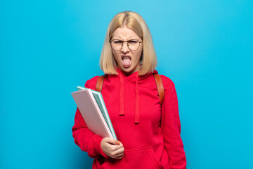 blonde woman feeling disgusted and irritated, sticking tongue out, disliking something nasty and...