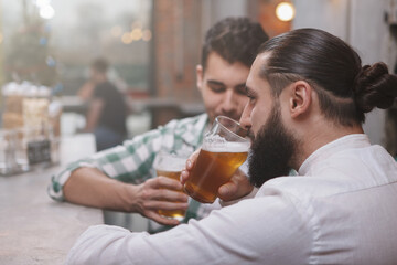 Rear view shot of a bearded man drinking beer at the pub with his friend