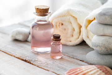 Natural organic spa products on wooden background. Essential rose oil, towel, stones. Atmosphere of relax, detention, zen. Aromatherapy. Body care, healthy lifestyle. Close up. Copy space for text.