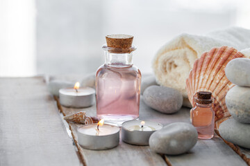 Fototapeta na wymiar Natural organic spa products on wooden background. Essential rose oil, towel, stones. Atmosphere of relax, detention, zen. Aromatherapy. Body care, healthy lifestyle. Close up. Copy space for text.