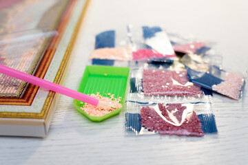 home hobby to draw a picture of rhinestones, multicolored diamond mosaic. the process of gluing a pencil of rhinestones on the canvas of the picture