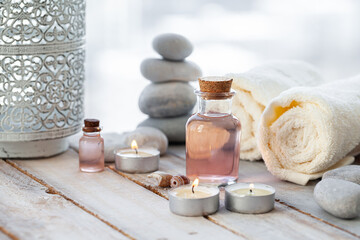 Fototapeta na wymiar Natural organic spa products on wooden background. Essential rose oil, towel, stones. Atmosphere of relax, detention, zen. Aromatherapy. Body care, healthy lifestyle. Close up. Copy space for text.