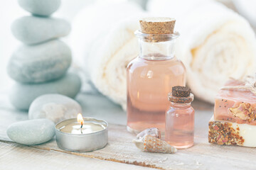 Obraz na płótnie Canvas Natural organic spa products on wooden background. Essential rose oil, towel, stones. Atmosphere of relax, detention, zen. Aromatherapy. Body care, healthy lifestyle. Close up. Copy space for text.