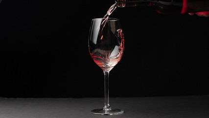 Pouring red wine from a bottle into a wine glass. isolated.