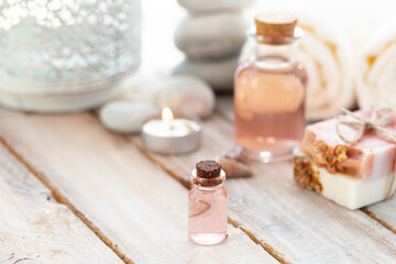 Natural organic spa products on wooden background. Essential rose oil, towel, stones. Atmosphere of relax, detention, zen. Aromatherapy. Body care, healthy lifestyle. Close up. Copy space for text.