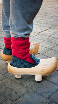 Piernas vistiendo pijama gris y calcetines rojos calzando zapatillas de andar por casa y zuecos tradicionales de madera 