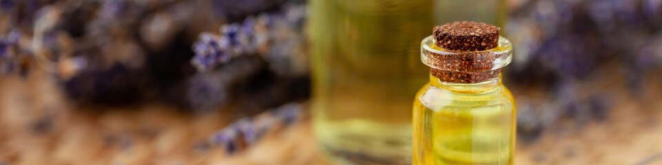 Organic natural essential lavender oil in glass bottles. Dry flowers, wooden background. Spa products for relaxation, aromatherapy. Herbal cosmetics. Close up, macro, copy space for text. Banner