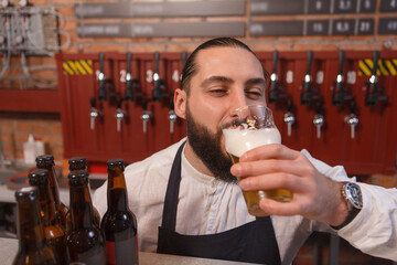 Bartender sipping delicious beer, closing eyes in pleasure
