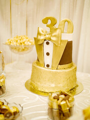 Handsome golden birthday cake for a man in the form of the number thirty on a light background