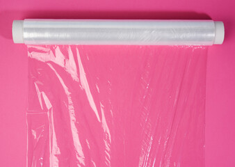 roll of transparent cling film on pink background