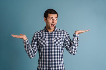Excited young caucasian guy holding and showing copyspce