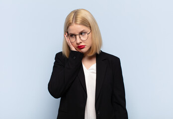 blonde woman feeling bored, frustrated and sleepy after a tiresome, dull and tedious task, holding...