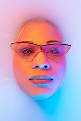 Calm. Beautiful female face in the milk bath with soft glowing in blue-pink neon light. Copyspace for advertising. Modern neoned colors, foam. Beauty, fashion, style, skincare concept. Attractive.