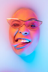 Gremaces. Beautiful female face in the milk bath with soft glowing in blue-pink neon light. Copyspace for advertising. Modern neoned colors, foam. Beauty, fashion, style, skincare concept. Attractive.