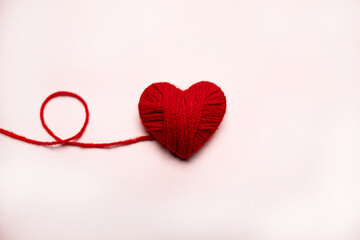 Red heart made of wool on a white background