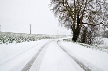 A snowy country road, dangerous and slippery during winter snowfall.