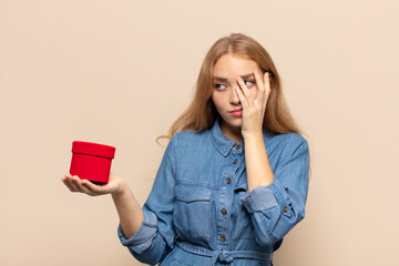 blonde woman feeling bored, frustrated and sleepy after a tiresome, dull and tedious task, holding...