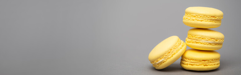 delicious yellow macarons on grey background, banner