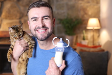 Man holding baby wild cat and feeding bottle