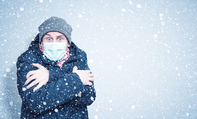 Fototapeta na wymiar Frozen man in winter clothes on his face wearing a respirator mask to protect against the virus covid, snow around