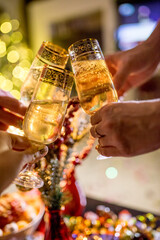 champagne glasses in the hands of friends on the background of a Christmas tree and New Year decor
