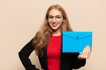 blonde woman smiling happily with a hand on hip and confident, positive, proud and friendly attitude