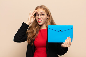 blonde woman looking happy, astonished and surprised, smiling and realizing amazing and incredible...