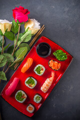 Valentine day festive dinner idea. Menu, invitation background for Valentine day sushi roll set, with heart shaped decor and rose flowers bouquet. Top view with copy space for text